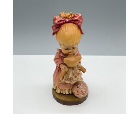 Limited edition hand carved figure of a young girl with a bow in her hair giving her teddy bear a good morning kiss. Anri and