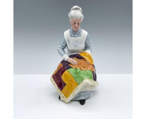 Hand decorated and hand painted figure an seated elderly woman with a quilt on her lap. Blue, white, green, yellow and red co