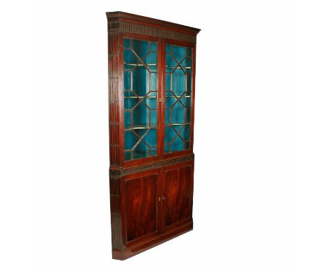 A George III mahogany double corner cabinet, c.1780, with canted corners and carved frieze, the two-door top with glazed astr