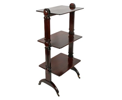 An early Victorian mahogany three-tier whatnot or buffet, c.1840, with rounded rectangular shelves between decorative carved 