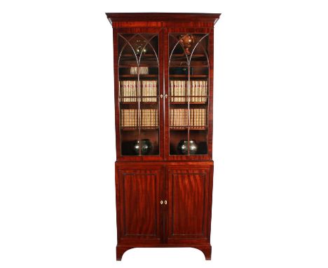 A George III mahogany cabinet bookcase, the flared overhanging cornice and banded frieze above a pair of glazed astragal door