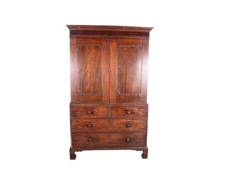 A George III mahogany linen press, with dentil cornice above a pair of panel doors enclosing shelves and clothes trays, the l