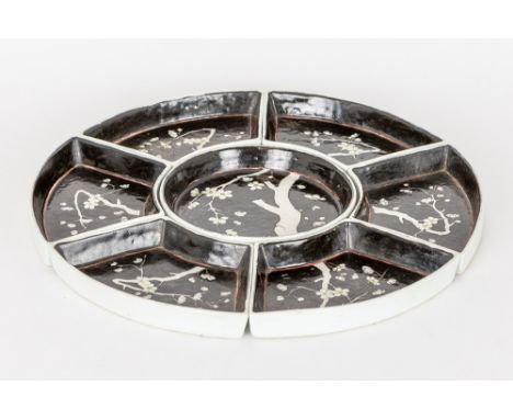 Chinese set with a central round plate surrounded by six curved ones in porcelain with a blossoms decor on a black background