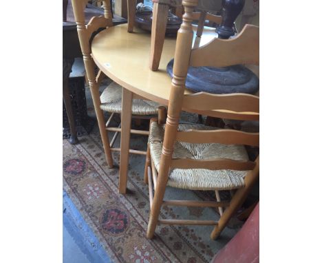 A light wood extending table and four rush seated ladder back chairs. 