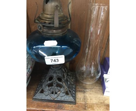 A Victorian oil lamp with king fisher blue cut glass reservoir and cast metal base depicting mythical dolphins. 