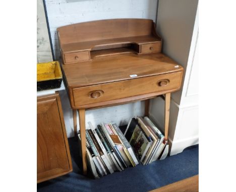 ERCOL: A PALE ELM DESK fitted a long drawer and two small drawers, 27" wide