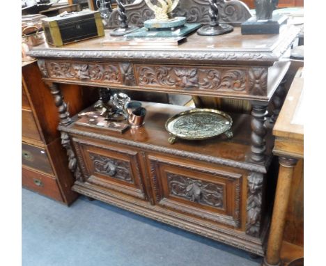 A VICTORIAN CARVED OAK BUFFET with mask handled drawers and twin cupboard door below, 48" wide 