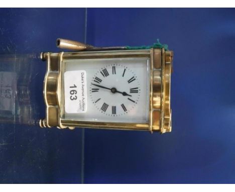 AN EDWARDIAN BRASS-CASED CARRIAGE CLOCK with bevelled glass panels and enamel dial, 4.5" high
