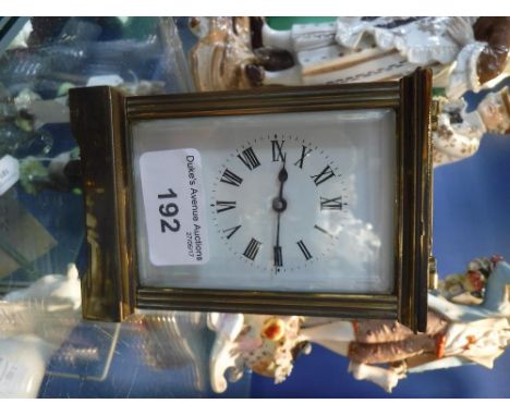 A BRASS CARRIAGE CLOCK with bevelled glass panels and enamel dials, 4.5" high