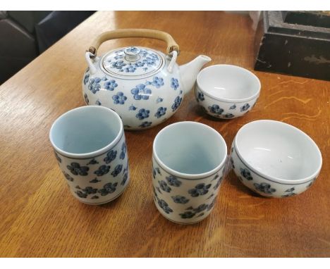 A Japanese blue and white porcelain tea set, in the prunus pattern, comprising a teapot with swing handle, two cups and two b