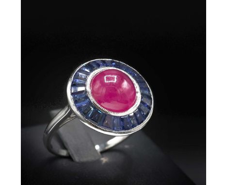 AN 18CT WHITE GOLD RUBY AND SAPPHIRE TARGET RING. in the Art Deco style, set with a ruby cabochon and calibre cut sapphires; 