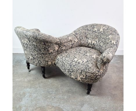 NAPOLEON III CONVERSATION SOFA. Ebonised in elephant patterned fabric on castors, 76cm H x 150cm W.