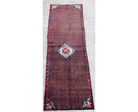 A Persian Kordi woollen hand knotted runner with central geometric gul on a blue ground, 285 by 81cms (112 by 32ins).