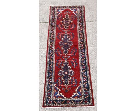 A Persian Hamadan woollen hand knotted runner with repeat foliate guls on a red ground, 283 by 98cms (111.5 by 38.5ins).