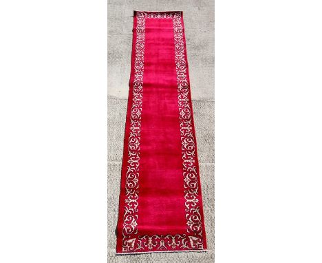 A Persian Tabriz woollen hand knotted runner with stylised borders on a claret ground, 380 by 80cms (149.5 by 31.5ins).