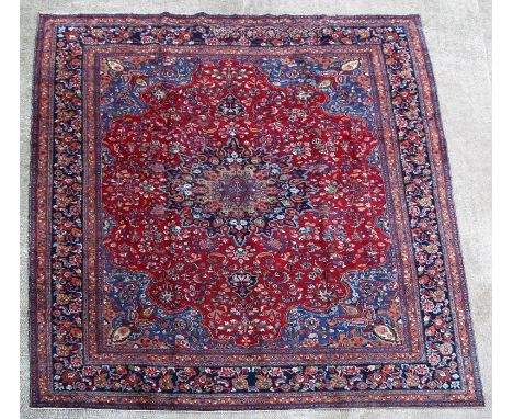 A Persian Mashad woollen hand knotted carpet with central floral medallion within floral borders, on a blue ground, 397 by 29