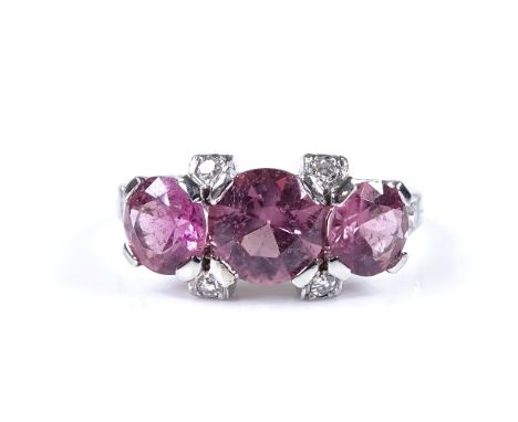 An unmarked white gold pink tourmaline and diamond trilogy ring, with diamond set shoulders, unmarked settings test as 18ct w