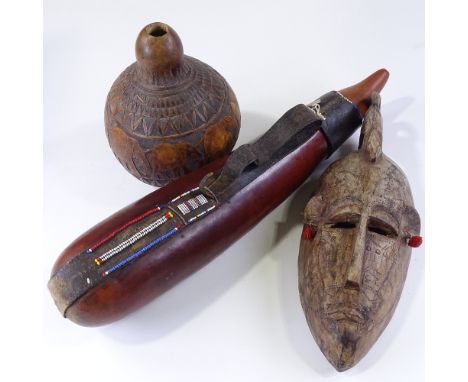 An African carved wood Tribal mask, length 40cm, a beadwork mounted leather gourd, and an elephant carved gourd flask (3) 