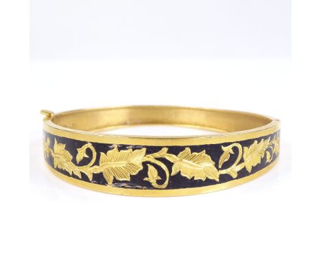 A Middle Eastern unmarked gold and black enamel hinged bangle, with engraved leaf decoration, band width 10.8mm, internal dia