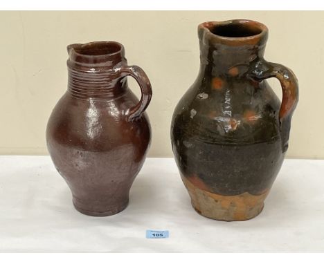 An 18th Century salt glazed jug, 11½ high (cracked) and an antique green glazed earthenware pitcher, 13" high.