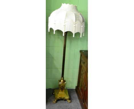 A gilt metal corinthium column standard lamp, raised on paw feet and with silk fringed shade