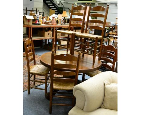 A set of six oak framed ladder back dining chairs with rush seats with matching circular dining table