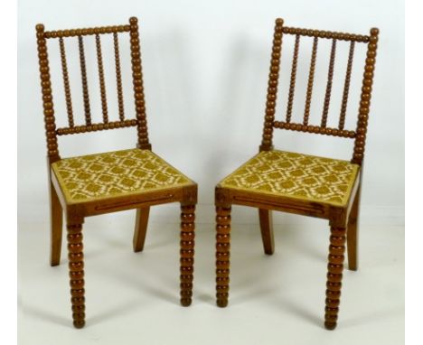 A pair of Victorian Aesthetic bobbin turned oak chairs, seats upholstered in foliate flocked beige fabric, 42 by 60 by 88cm h