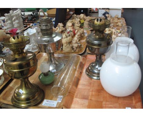 Two trays with three brass and white metal oil lamps, with three glass chimneys and two opaline glass shades and a small gree