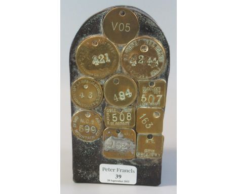 Tin miners arch shaped lunch box mounted with various brass miners talleys, some Welsh. 17.5cnm high. (B.P. 21% + VAT)