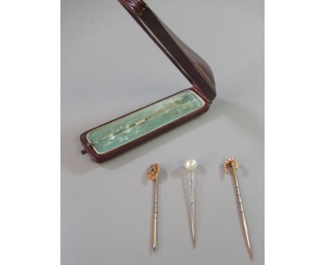 15ct gold horseshoe seed pearl set stick pin, another pearl stick pin and a 9ct gold stone set stick pin. In vintage red leat