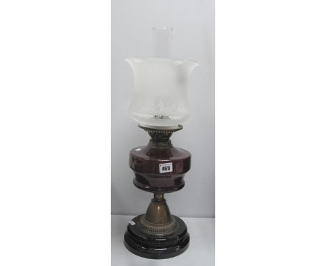 An Oil Lamp, circa 1900 with black glazed terracotta base and ruby glass well.