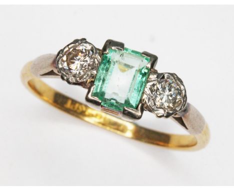 A diamond and emerald ring, central stone weighing approx. 0.54ct, set between two round cut diamonds weighing approx. 0.12ct