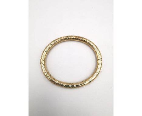 A modern Pobjoy mint 9 carat yellow gold bangle with criss-cross design. Opens with hidden push clasp. Hallmarked: PM, 375, S