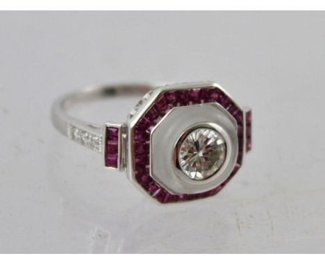 AN ART DECO STYLE DIAMOND AND RUBY RHODIUM FINISHED WHITE GOLD COLOURED METAL DRESS RING, having central millegrain brilliant