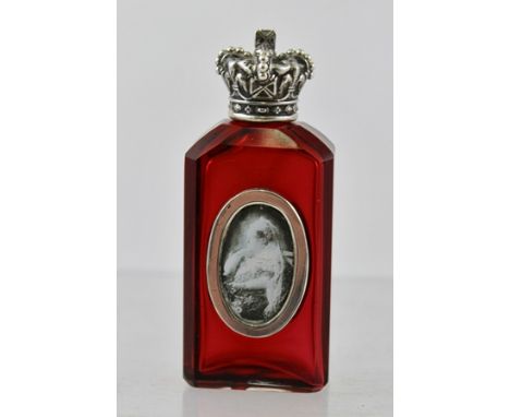 A SILVER CAPPED RUBY GLASS FACETTED SCENT BOTTLE, having a screw fit cap fashioned as a crown, and oval applied body with an 