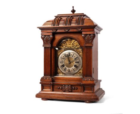A Junghans bracket clock, gong strike, silver tone dial with Roman numerals on brass with ornate cherub centrepiece and spand