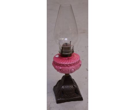 A Victorian oil lamp with Art Nouveau metal base, rose glass centre and clear shade, height 50cm.