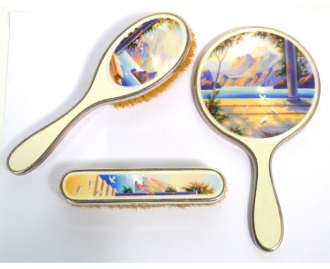 An unusual early 20th century child's silver and enamel decorated three piece dressing table set comprising hand mirror, hair