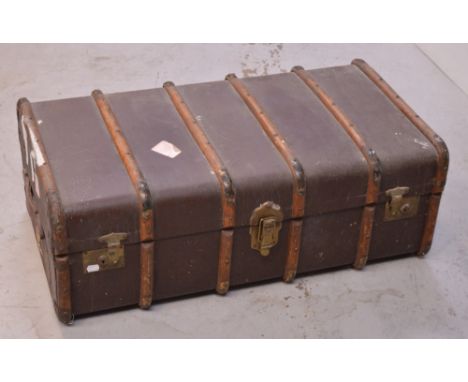 An early 20th century steamer trunk with oak binds and brass locks, brass corners, red leather handles and partial labels, ap