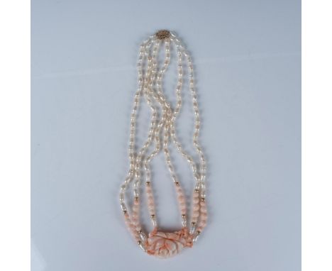 A beautiful three-layered necklace adorned with opalescent pearls and pink coral beads accenting the carved pink coral flower