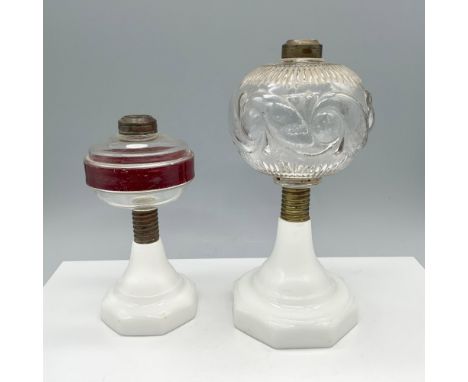 Traditional duo of table oil lamps with milk glass bases that includes a lamp with a cranberry red stripe on the body, and an