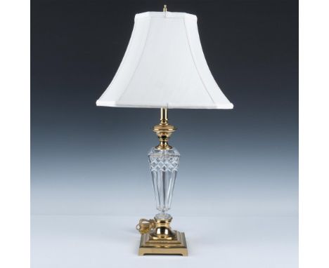 A stunning crystal lamp carved with intricate diamond and ridged patterns, featuring a gold colored base and neck, complement