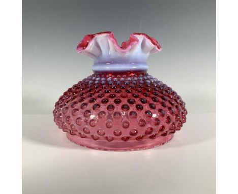A cranberry colored glass lamp shade with a round body adorned with high relief dots, a lavender neck, and a flower like mout
