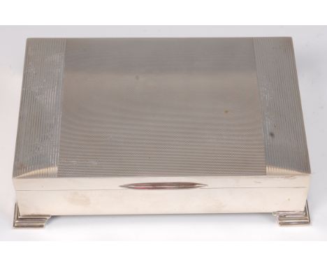 An Art Deco style silver table cigar box, having engine turned hinged cover and on stepped protruding feet, the twin division