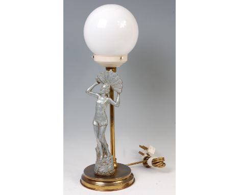 An Art Deco table lamp, mounted with a spelter figure of a standing lady holding a peacock fan, having milk glass globe shade