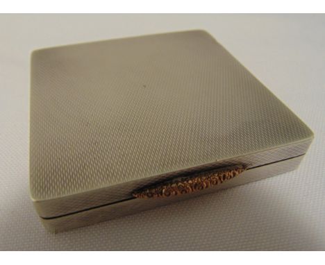 A hallmarked silver rectangular engine turned compact, the hinged cover with scroll thumb piece