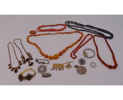 A quantity of costume jewellery to include a butterscotch amber graduated bead necklace, brooches, a ring and a wristwatch