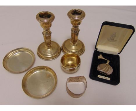 A quantity of hallmarked silver to include a pair of candlesticks, a pair of coasters, a napkin ring, a white metal miniature