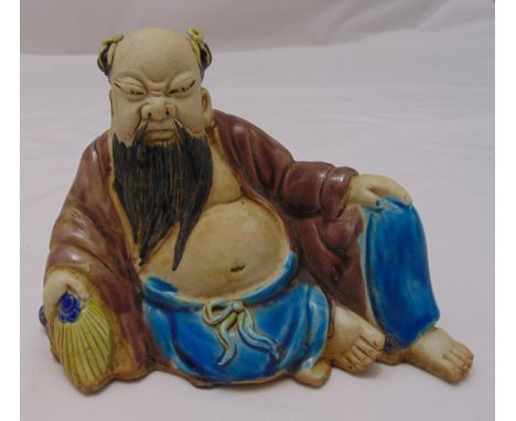 An oriental ceramic figurine of Lohan in relaxed pose, 11cm (h)