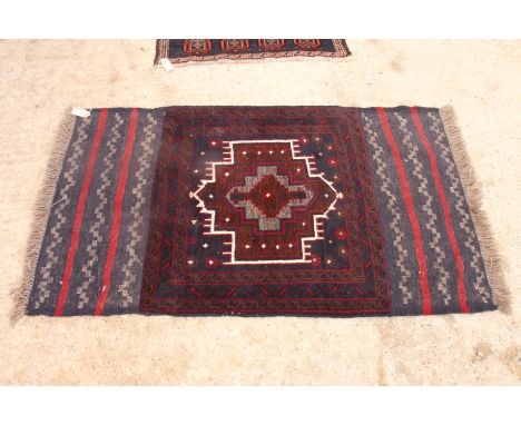 An Afghan Belouch rug decorated central medallion on a dark blue ground, 56" x 33" approx